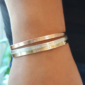 stack of cuff bracelets in sterling silver, rose gold and yellow gold on a woman's wrist